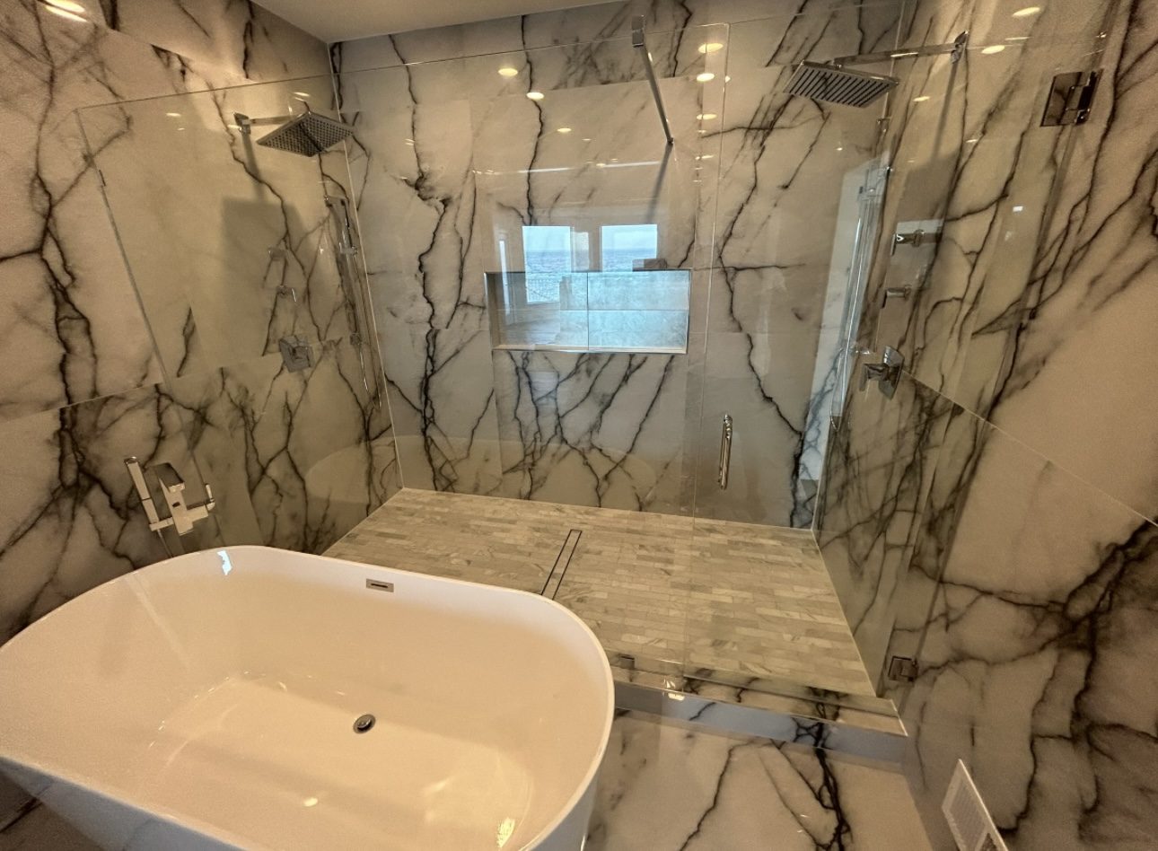 Marble wet room with book-matched slab walls, freestanding tub and teak bench, tile work by Mount Vernon Construction